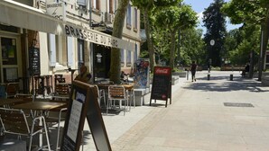 An outdoor café with tables and chairs, a sign for 'BRASSERIE DU PARC', and a Coca-Cola advertisement.
