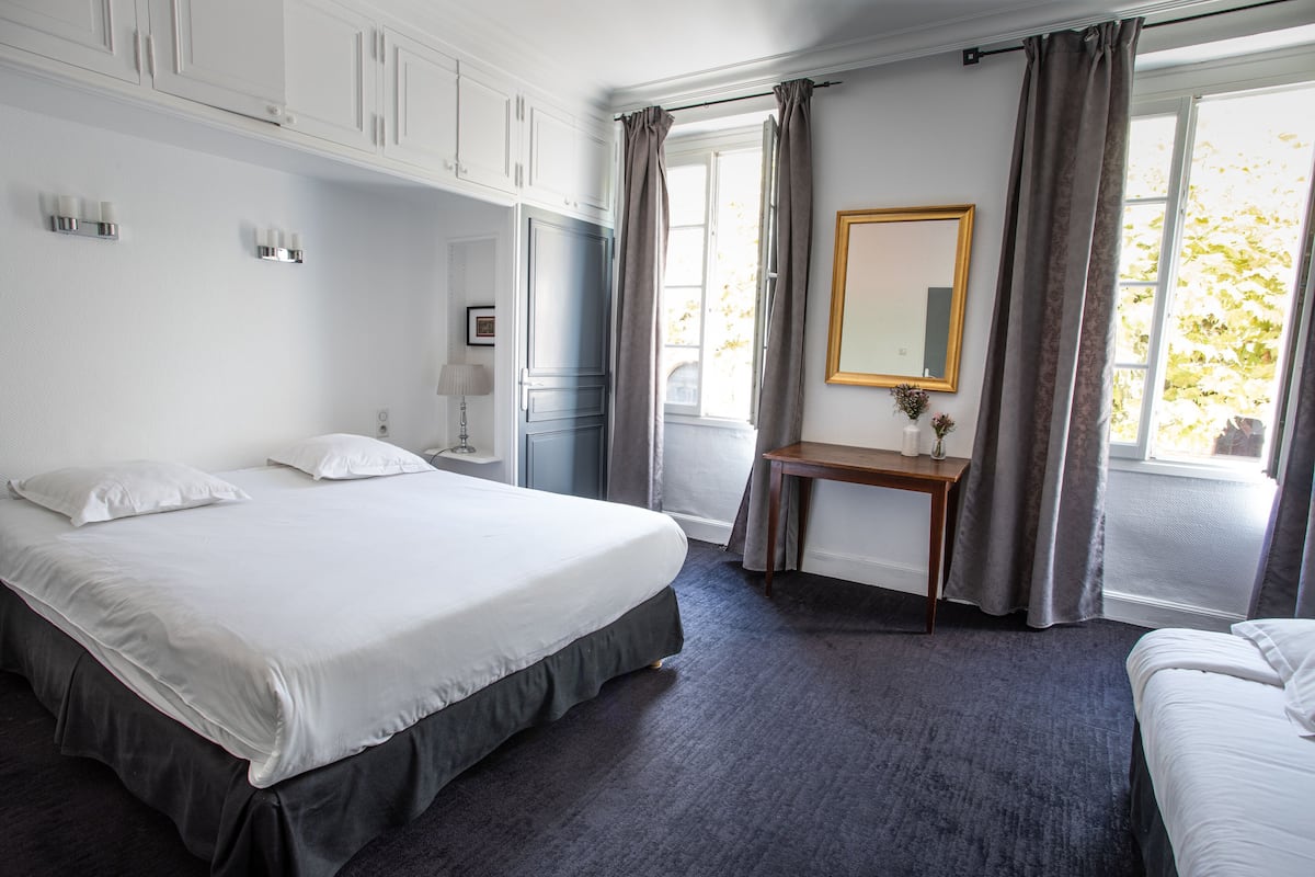 Een hotelkamer met een groot bed, een nachtkastje, een spiegel en een raam met gordijnen.