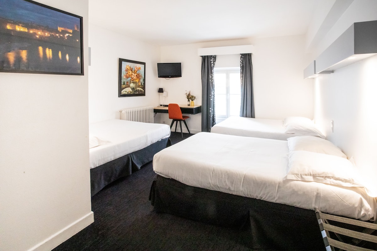 Een hotelkamer met twee bedden, een bureau, een stoel, een televisie en een raam met gordijnen.