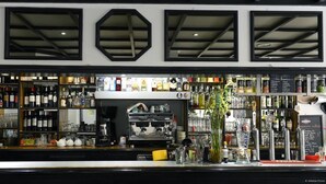 A bar with shelves of bottles, a coffee machine, and a chalkboard menu.