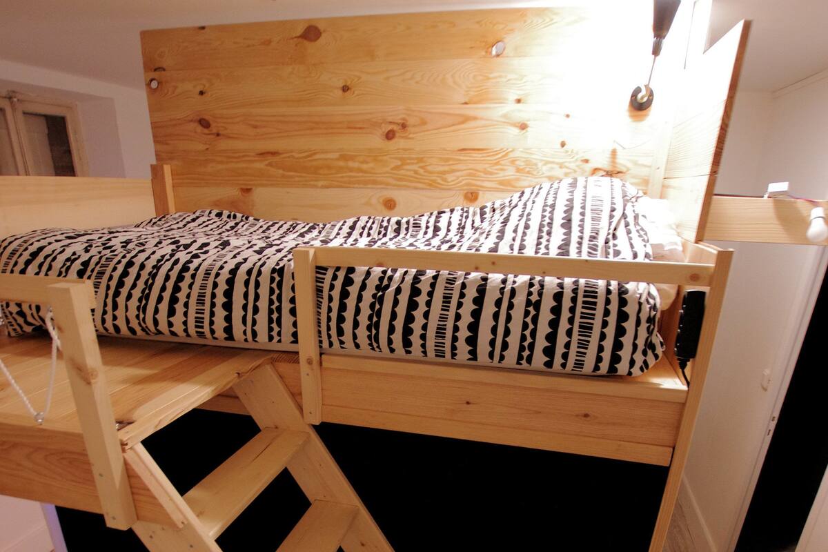 Un lit superposé avec une tête de lit en bois et une échelle.