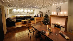A cozy living room with a wooden dining table, a sofa, and a Christmas tree. - Hostel les Cordées Liées (Albi)