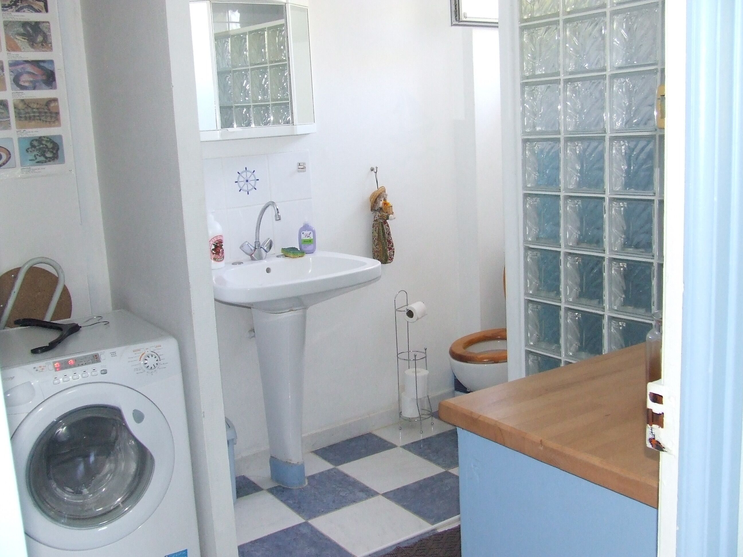 A compact bathroom with a washing machine, a sink, and a toilet.