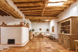 Un intérieur rustique avec un plafond en bois, une cheminée, un canapé et un meuble en bois.