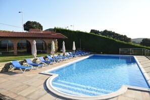 A rectangular swimming pool with a tiled edge, surrounded by blue lounge chairs and white umbrellas. - Luxury apartment with swimming-pool and tennis court. Beach 600m. (Mogro)
