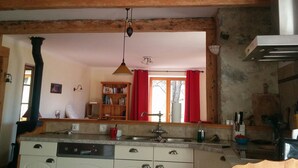 A kitchen with wooden beams, a central island with a sink, and a hanging light fixture.