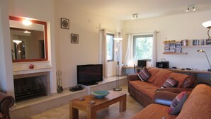 A living room with a fireplace, a television, a sofa, and a coffee table. - Rejuvenate family & friends at Stunning Villa Estia - close to beach & tavernas. (Makry Gialos)