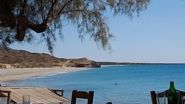 A beachside table with chairs and a green bottle, overlooking a clear blue sea and sandy beach. - Rejuvenate family & friends at Stunning Villa Estia - close to beach & tavernas. (Makry Gialos)
