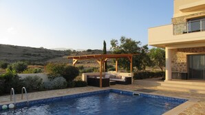 A swimming pool with a wooden pergola and outdoor seating, surrounded by stone walls and vegetation. - Rejuvenate family & friends at Stunning Villa Estia - close to beach & tavernas. (Makry Gialos)