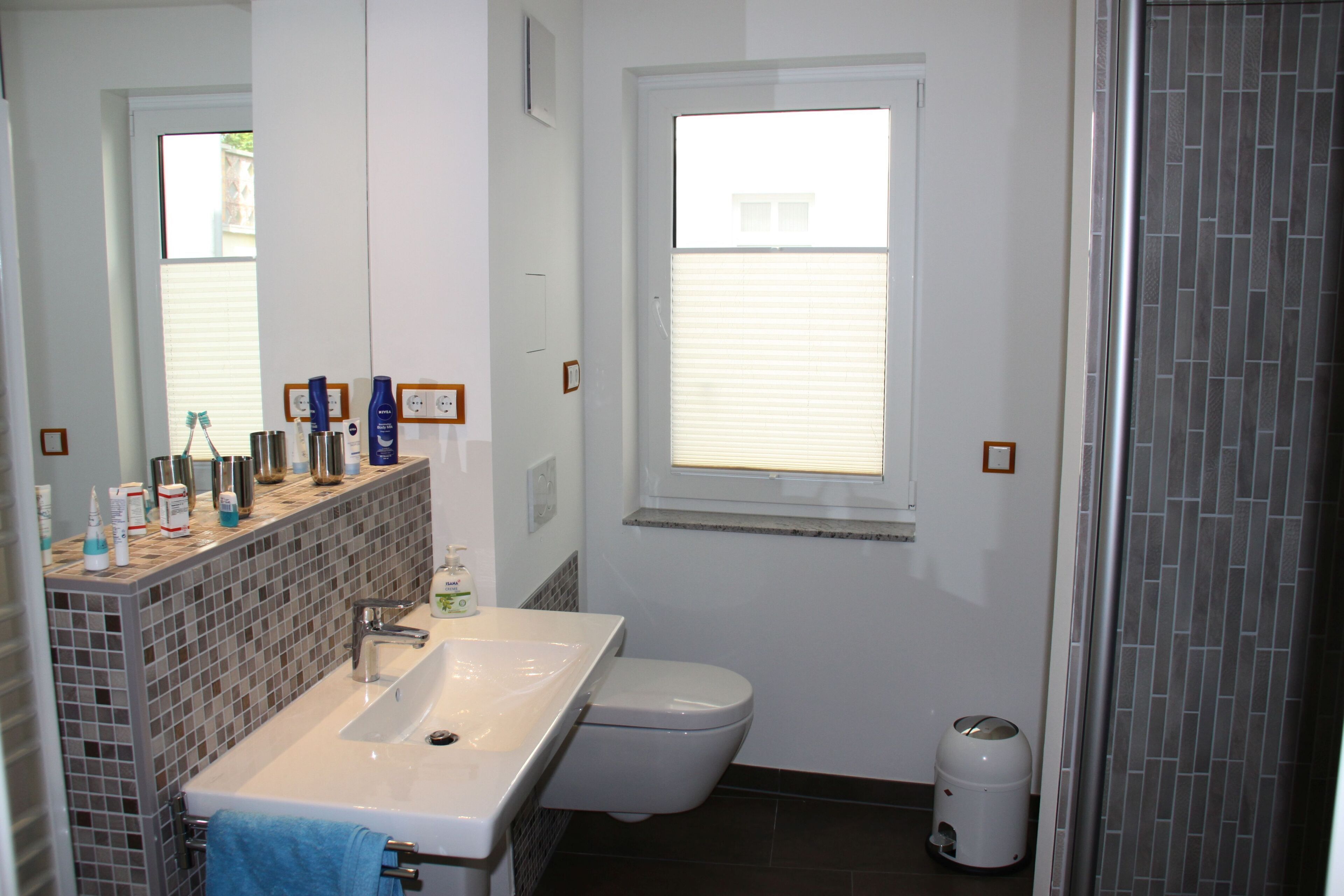 A bathroom with a white sink, a toilet, and a window with blinds.