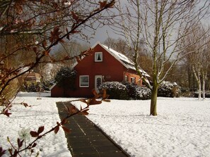 Ein rotes Backsteinhaus mit einer schneebedeckten Rasenfläche und einem Weg zum Eingang.