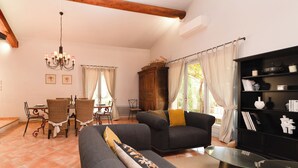 Un salon comprenant un canapé, une table basse en verre, un meuble en bois et un coin repas avec des chaises et une table.