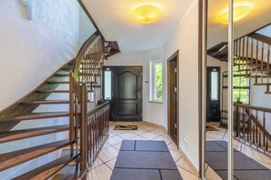 Un escalier avec des rampes en bois menant à une porte sombre dotée d’une fenêtre.
