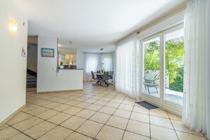 A spacious interior with a tiled floor, a kitchen area, and a dining space with a view of greenery outside. - Holiday house with unforgettable sea views, fireplace, garage, WiFi,  (Pobierowo)