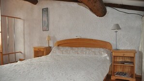 Une chambre à coucher avec un lit en bois, une table de chevet avec une lampe et une armoire en bois.