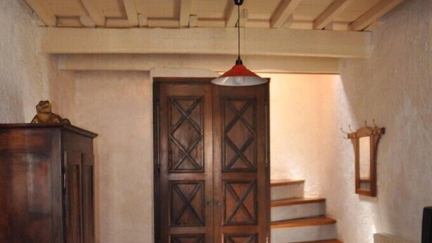 Un salon avec un canapé en bois, une table en bois et un escalier menant à l’étage supérieur.