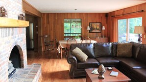 A cozy living room with a fireplace, a dining area, and a large window.