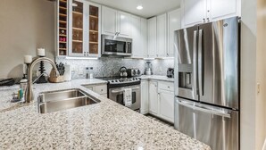 A modern kitchen with white cabinets, stainless steel appliances, granite countertops, and a built-in oven. - The Gant Luxury 2BR-2BA  Suite (Aspen)