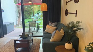 A living room with a sofa, a small table, a potted plant, and a view of the outdoors. - **Newly Renovated** Ground Floor Condo In Paradise (Kihei)