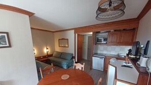 Un espacio habitable compacto con comedor, kitchenette y sofá.