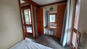 Un dormitorio con cama, escritorio y ventana con cortinas.