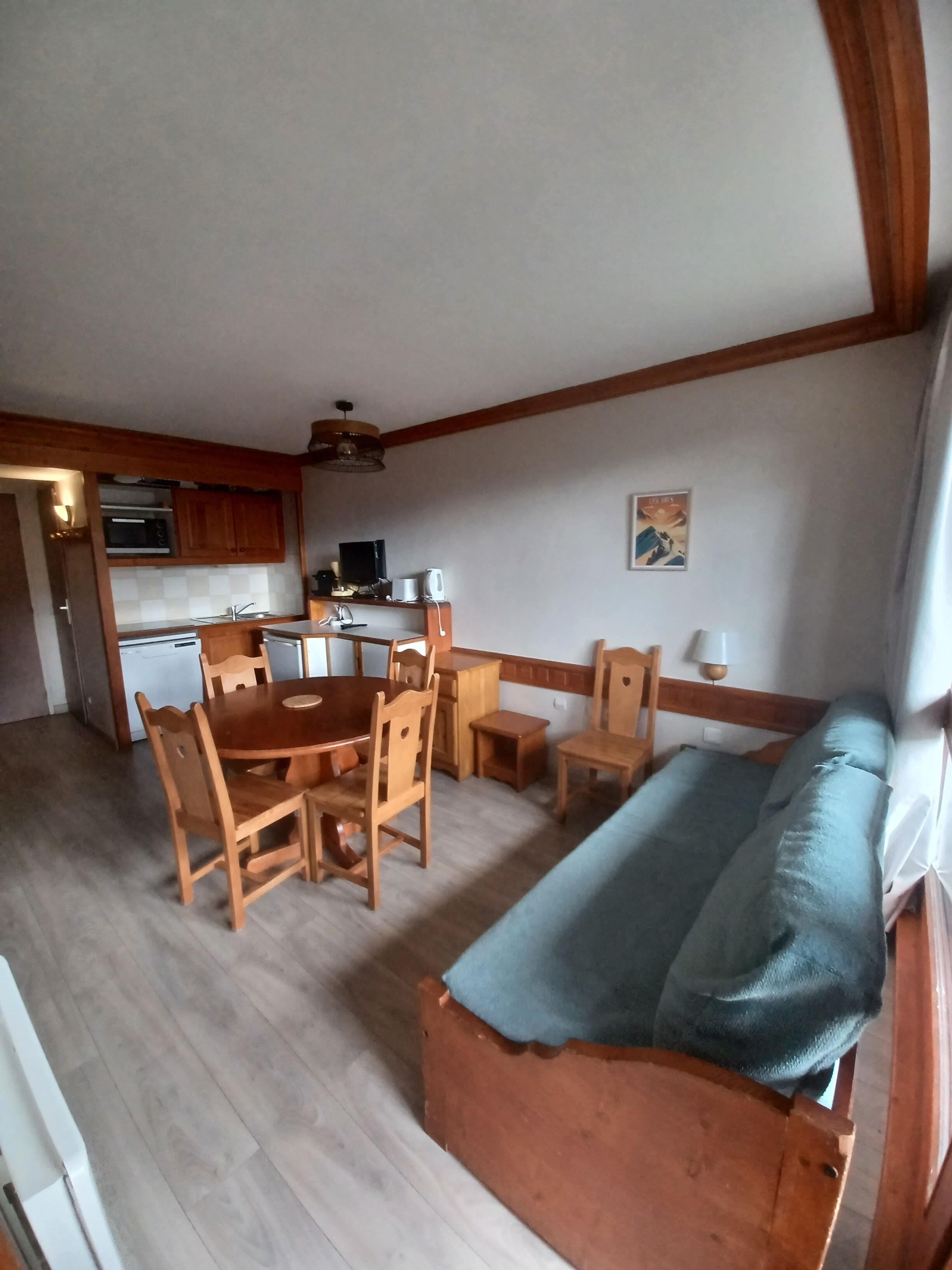 A compact living space with a dining area, kitchenette, and a sofa.