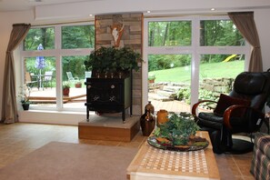 Un salón amplio con chimenea, ventanas grandes y vista al jardín.