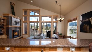 A spacious kitchen with granite countertops, a fireplace, and large windows offering mountain views.