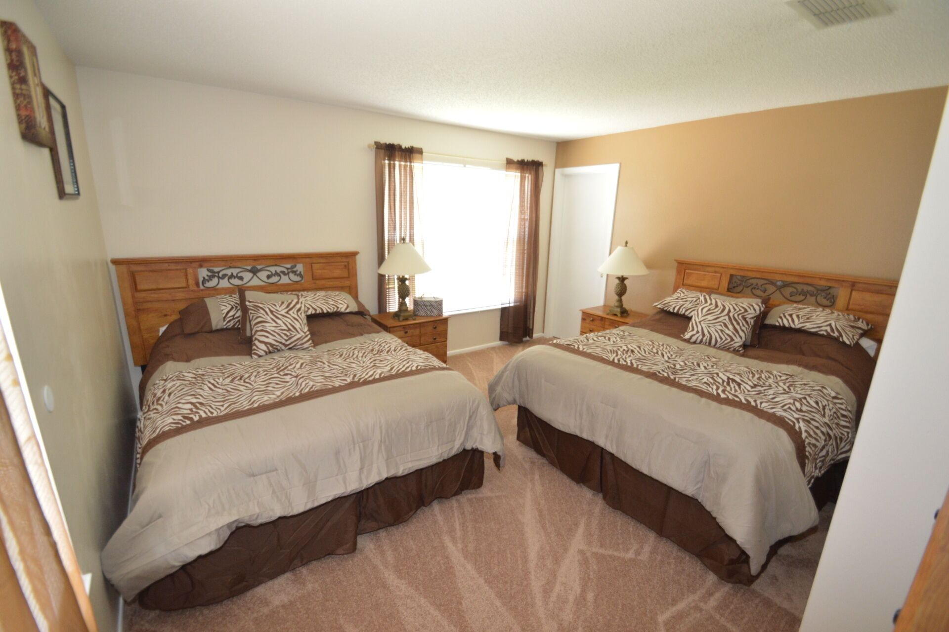 A double room with two beds, each with a zebra-patterned bedspread, a wooden headboard, and a nightstand with a lamp.