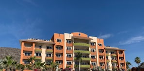 A multi-story hotel with balconies, a sandy beach in front, and palm trees. - Casa Bella Beachfront. In town. White Sandy Beaches & Palmas Pickleball Nextdoor (Los Barriles)