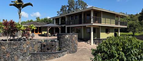 A two-story house with a stone pool, outdoor seating, and a covered patio.