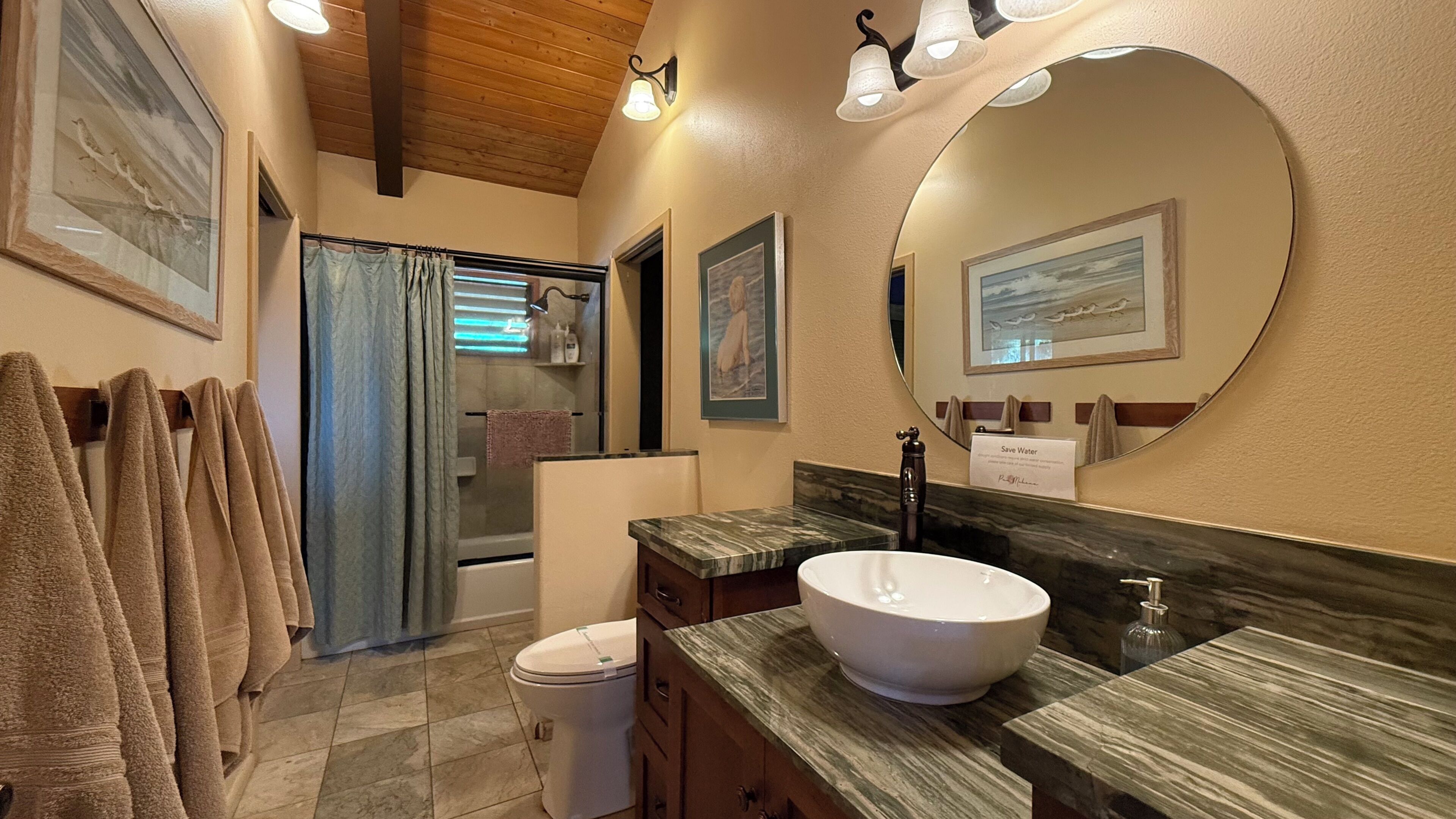 A bathroom with a large mirror, a sink, and a shower.