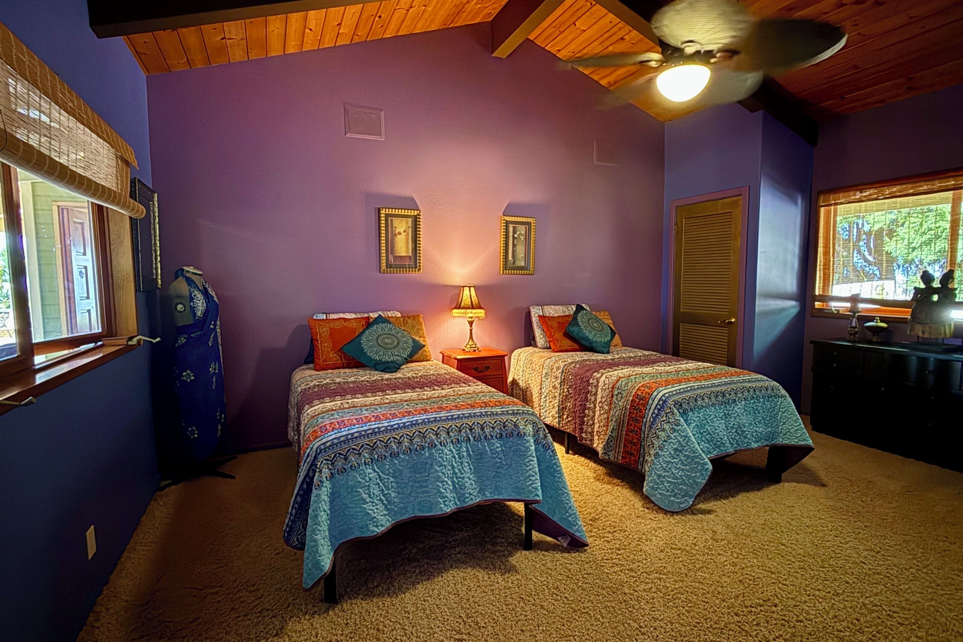 Un dormitorio con dos camas, un ventilador de techo y una ventana con vistas.