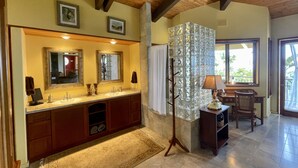 Une salle de bain spacieuse dotée d’un grand meuble-lavabo, de plusieurs miroirs et d’une cloison en verre décorative.