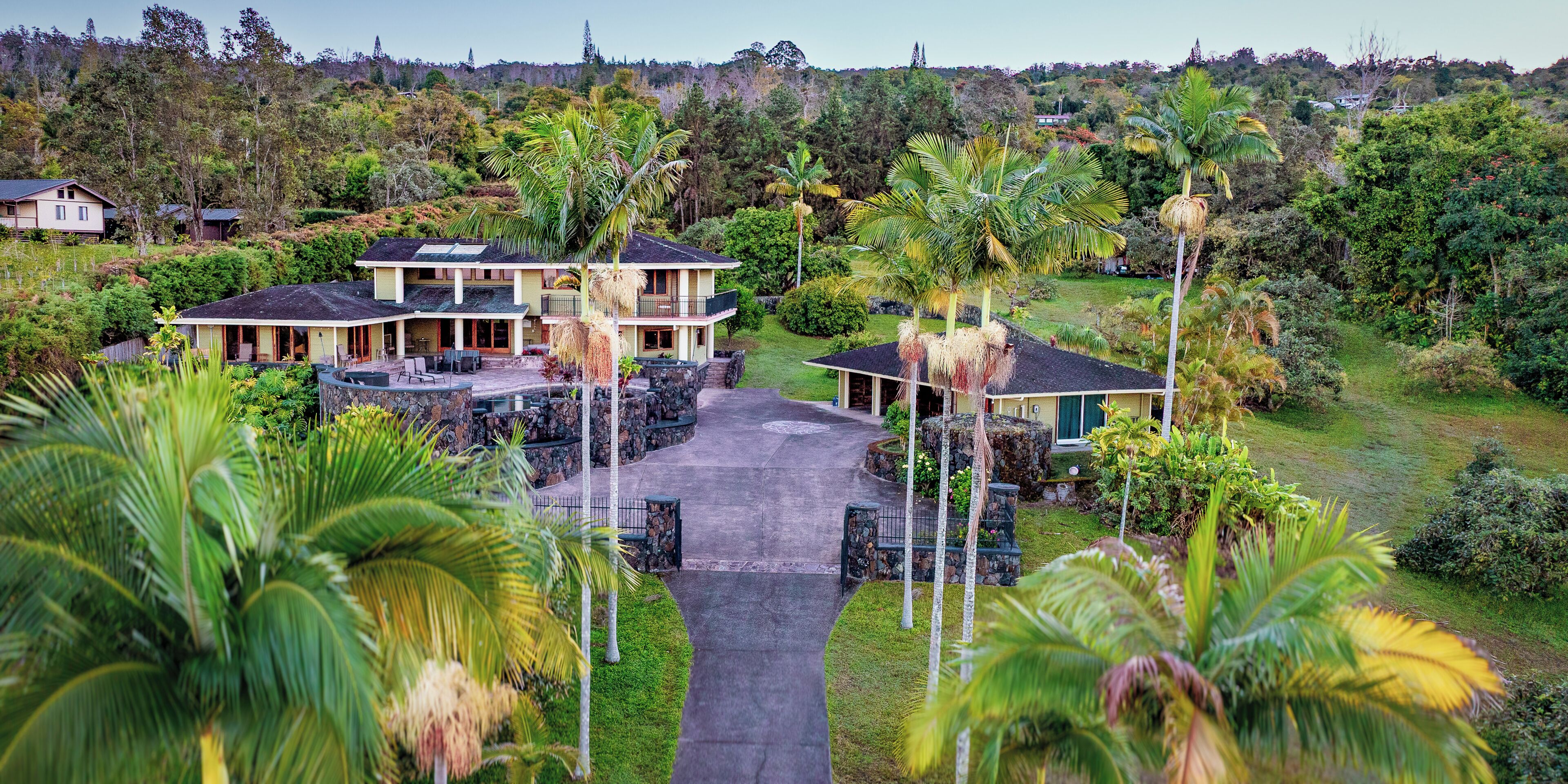 A large, two-story house with a paved driveway and multiple outdoor seating areas.