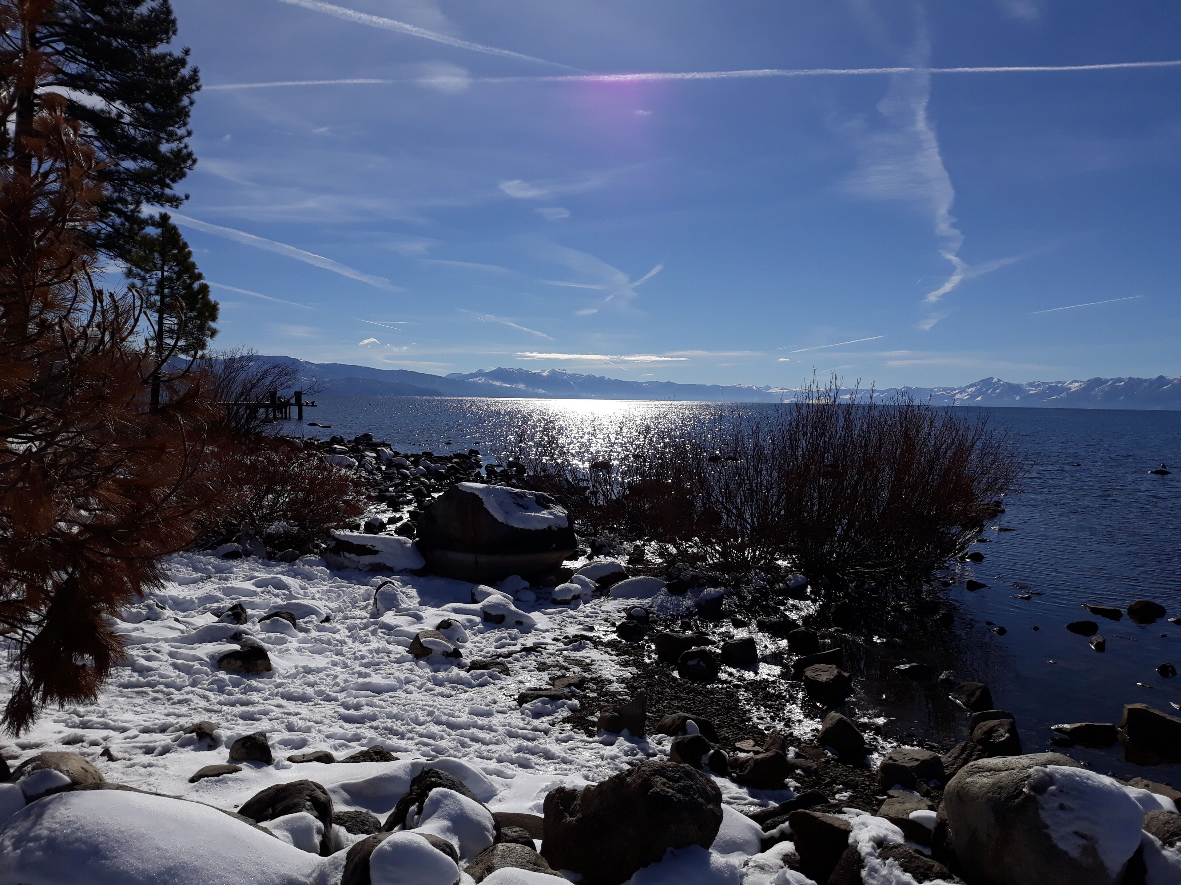 A snowy lakeside scene with mountains in the background.