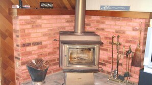 A wood-burning stove with a brick surround, a metal ash collector, and a sign that reads "Relax".