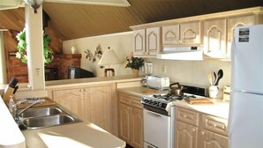 A kitchen with wooden cabinets, a stove, a sink, and a refrigerator.