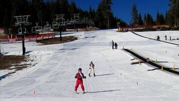 Pista de esquí con telesillas y árboles al fondo.