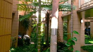 Un edificio de varios pisos con un atrium central que presenta altas palmeras y helechos.