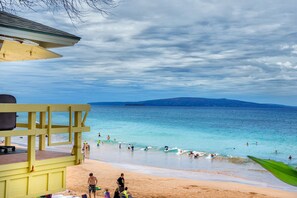 A beach with a lifeguard tower, clear skies, and calm waters. - OCEAN VIEW PENTHOUSE 2 BR 2 BATH @KAM 2&3 BEACHES WALK TO SHOPS & RESTAURANTS. (Kihei)