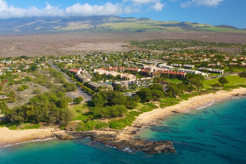 Luftaufnahme eines Küstenresorts mit Strand, Golfplatz und Wohngebiet.