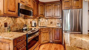 A kitchen with wooden cabinets, stainless steel appliances, granite countertops, and a granite backsplash. - Steps to gondola! Diamond rated! Lionshead Village! Pool & Hot Tub! Landmark 116 (Vail)