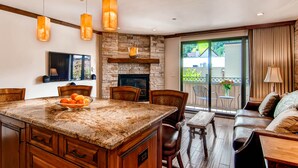 A kitchen with a large island, stone fireplace, and hanging pendant lights. - Steps to gondola! Diamond rated! Lionshead Village! Pool & Hot Tub! Landmark 116 (Vail)