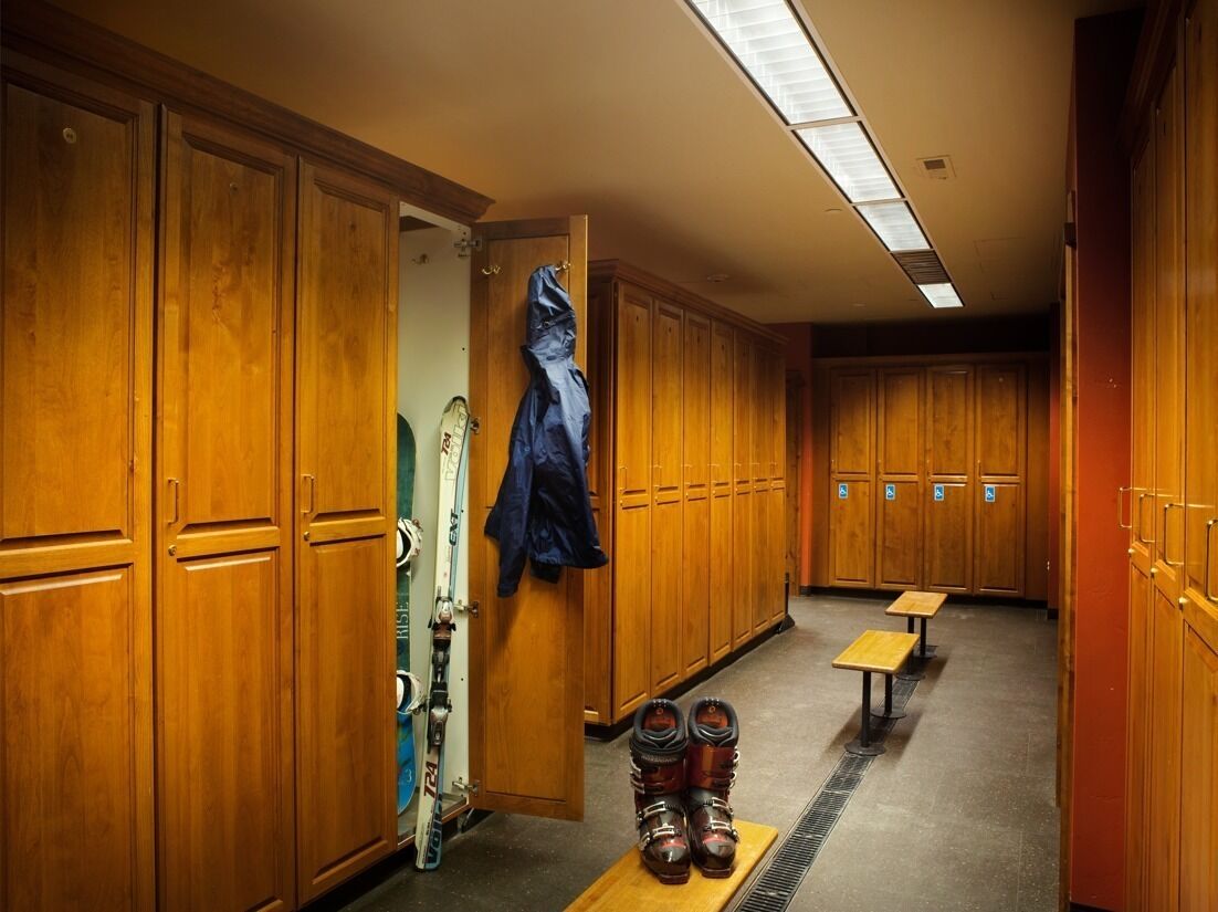 A locker room with wooden lockers, a bench, and a coat rack.