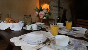 A breakfast table set with plates, cups, and a vase of flowers. - Château de Mayragues (Cahuzac-sur-Vere)