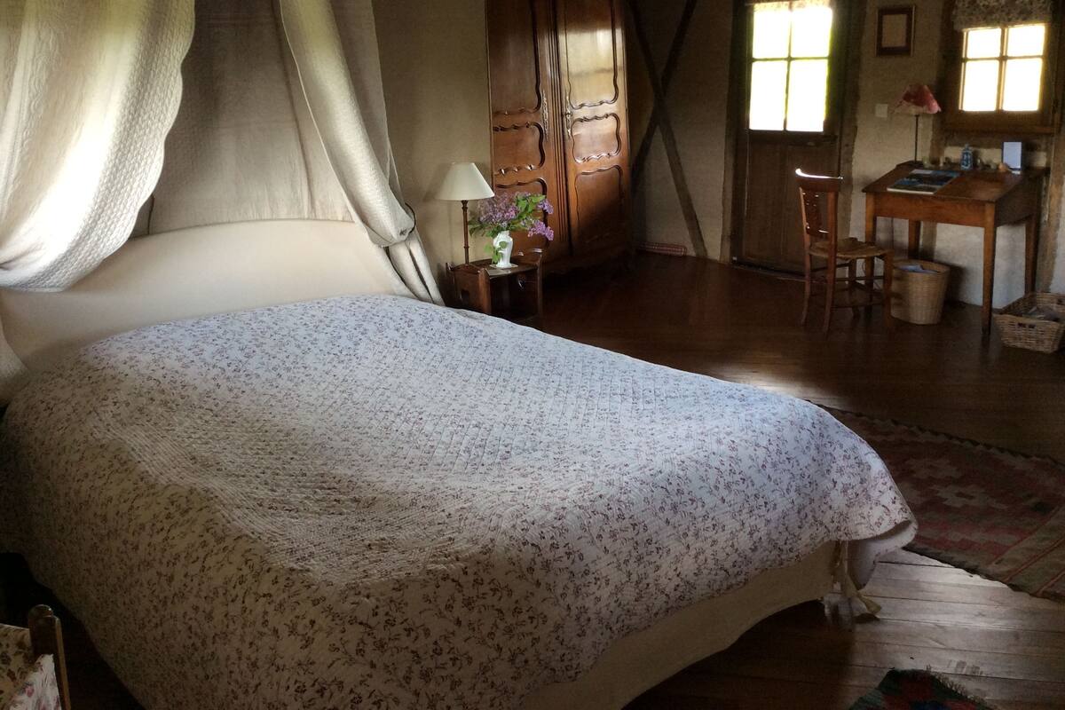 Een slaapkamer met een bed, een bureau en een stoel.