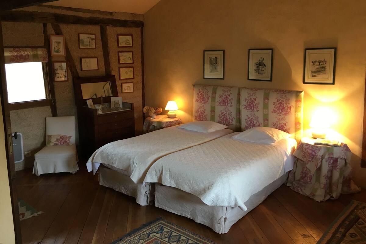 Een slaapkamer met twee bedden, een dressoir, een spiegel en ingekaderde foto's aan de muur.