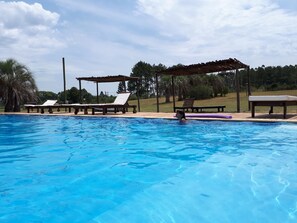 Una piscina al aire libre de temporada, sombrillas, tumbonas