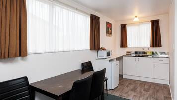 A compact kitchen with a dining area, white cabinets, a microwave, and a small refrigerator.